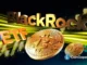 Ilustração 3D mostrando logo da BlackRock e símbolo ETF com moedas de Bitcoin douradas sobre fundo tecnológico com luzes amarelas e verdes.
