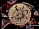 Moeda Bitcoin dourada fragmentada com gráfico de velas vermelhas ao fundo representando queda de preço.