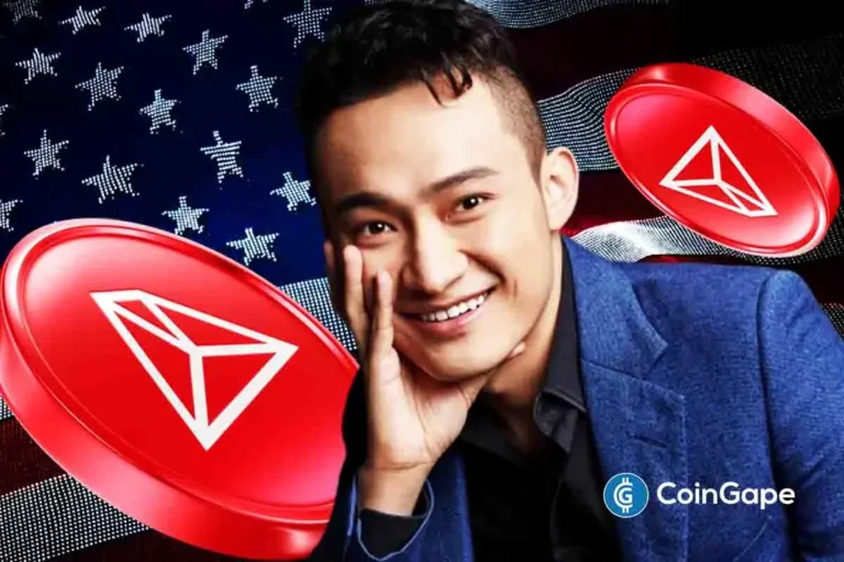 Foto de Justin Sun sorrindo em terno azul com logos vermelhos da TRON ao fundo da bandeira americana, representando a estreia da empresa na Nasdaq.