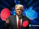 Donald Trump em coletiva de imprensa com moedas Bitcoin vermelhas e azuis flutuando ao redor em fundo tecnológico.