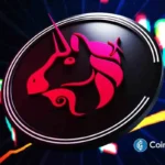 Logotipo do unicórnio Uniswap em vermelho e rosa dentro de uma lupa sobre fundo escuro com luzes coloridas desfocadas.